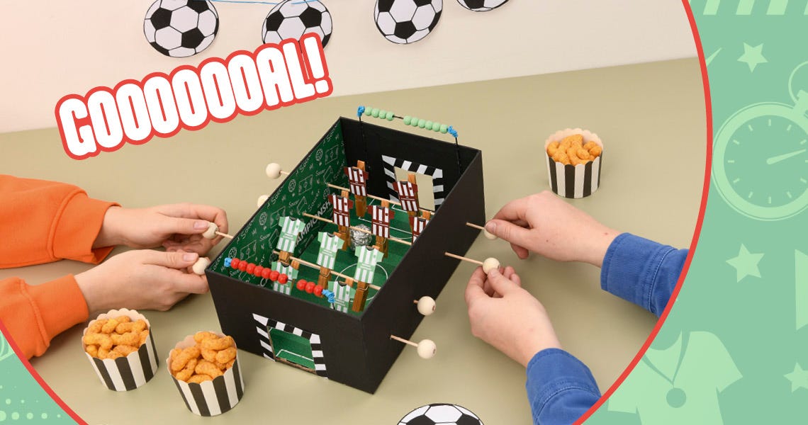 Zwei Kinder spielen an einem selbstgebastelten Tischkicker.
