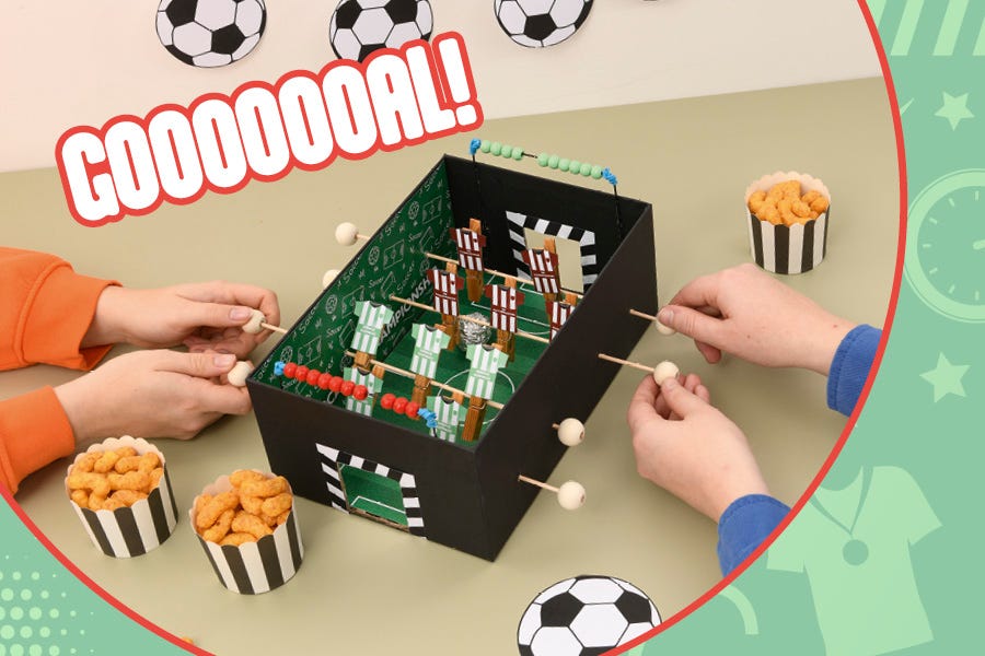 Zwei Kinder spielen an einem selbstgebastelten Tischkicker.